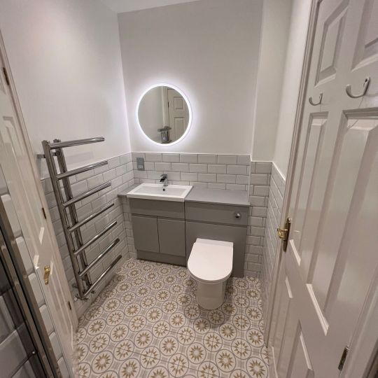 Round bathroom mirror with lighting around the circumference. Piha Plumbing and Bathroom Installations