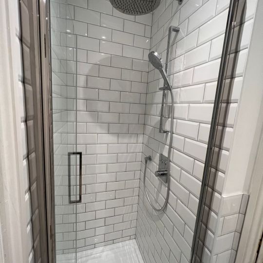 Large chrome shower rose. White tiled walls